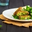 Vibrant green pea and mint fritters on a plate with a rocket side salad