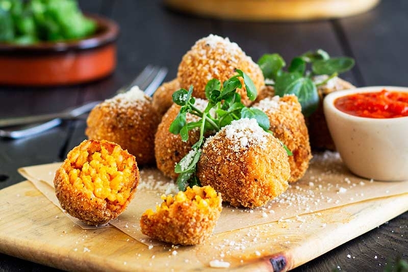 Tomato Arancini with grated parmesan on a serving board
