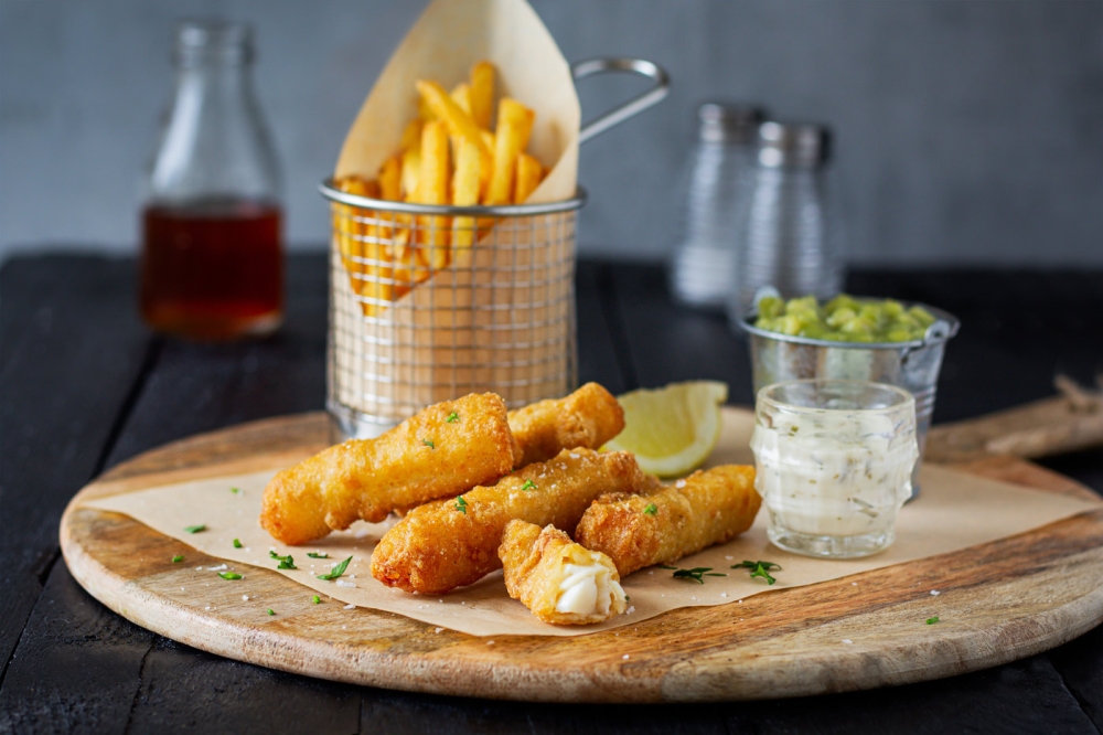 Battered Cod Goujons with chips and mushy peas on wooden board