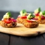 Sweetcorn Fritters topped with avocado on a wooden board