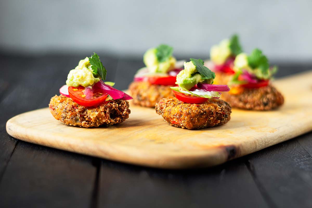 Sweetcorn Fritters topped with avocado on a wooden board