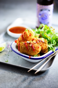 Mac and Cheese Croquettes in an enamel dish with a drizzle of chilli sauce